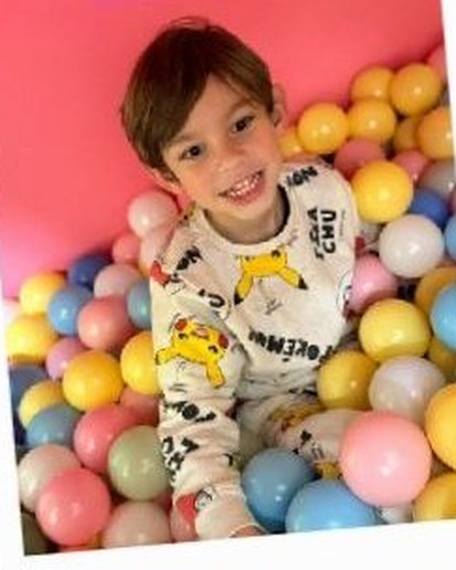 A happy child lying in a pastel ball pit