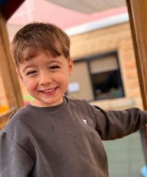 A child laughing outdoors in the sunshine
