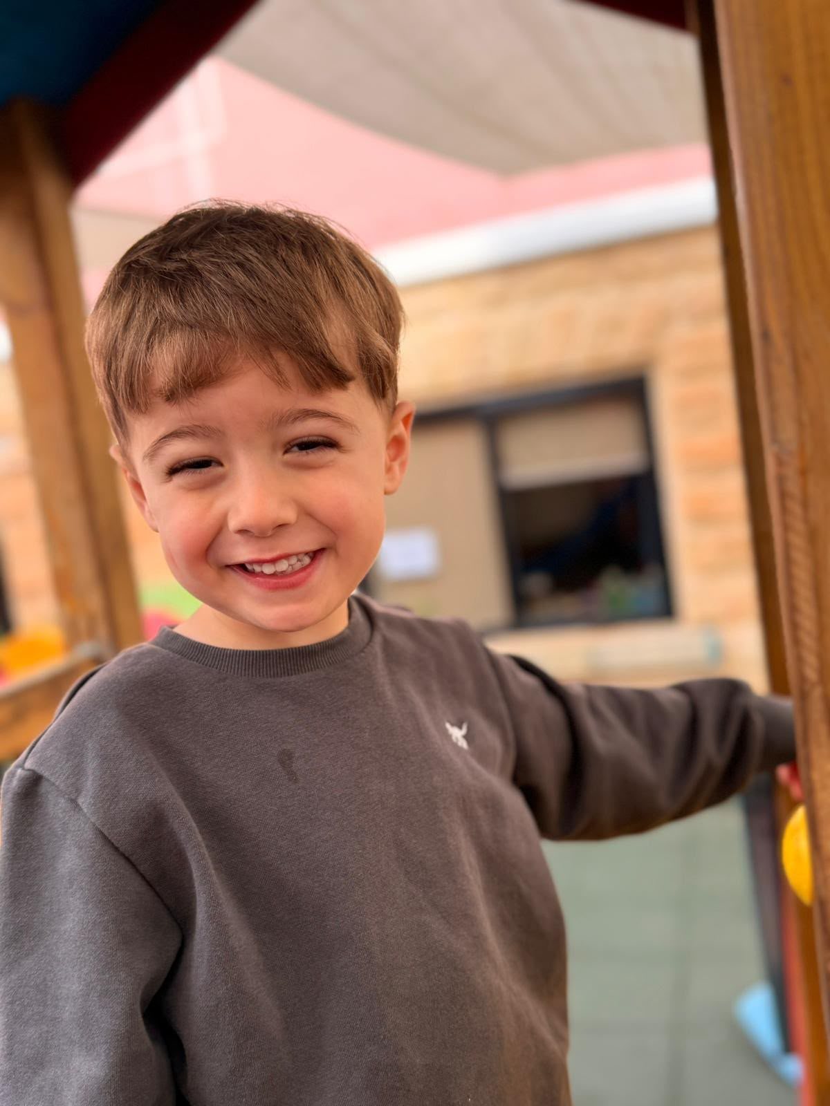 A child laughing outdoors in the sunshine