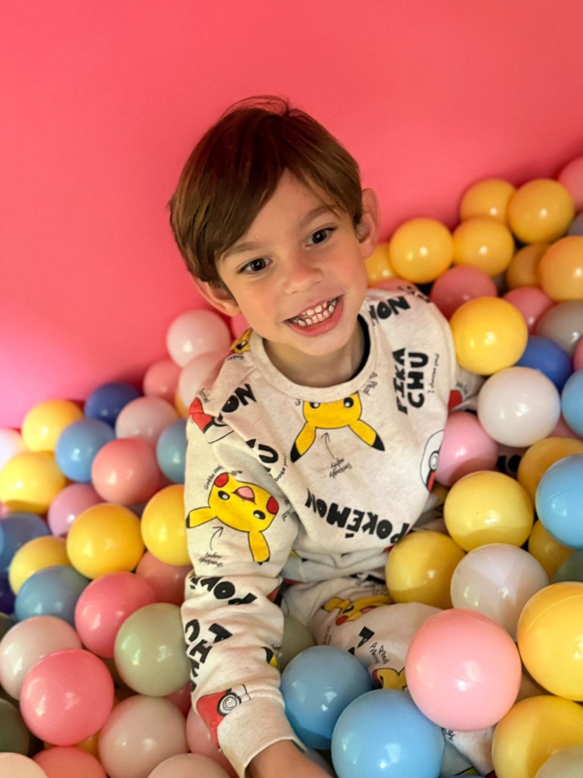 A happy child lying in a pastel ball pit